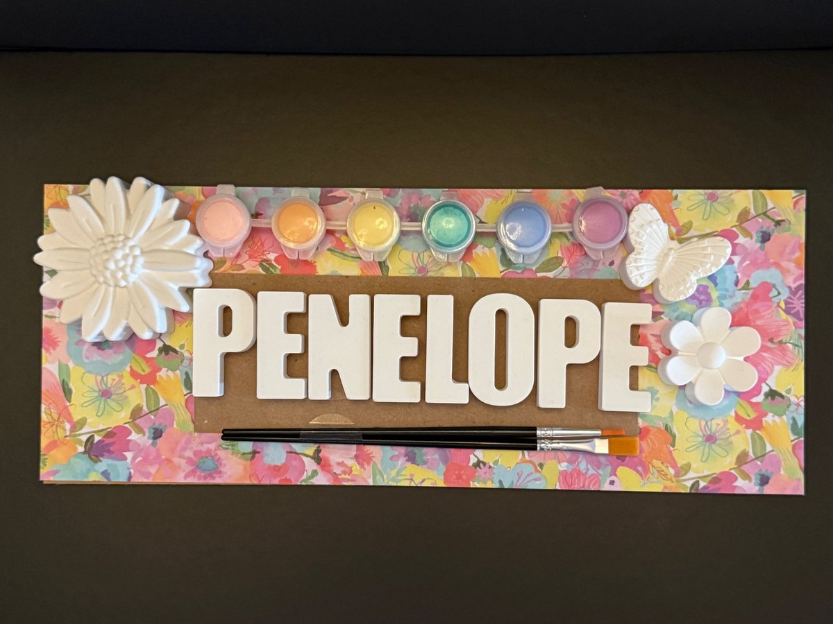 A Custom Name Kit spelling PENELOPE with a daisy, a butterfly and a flower on a floral board, six pastel paint pots and two brushes.