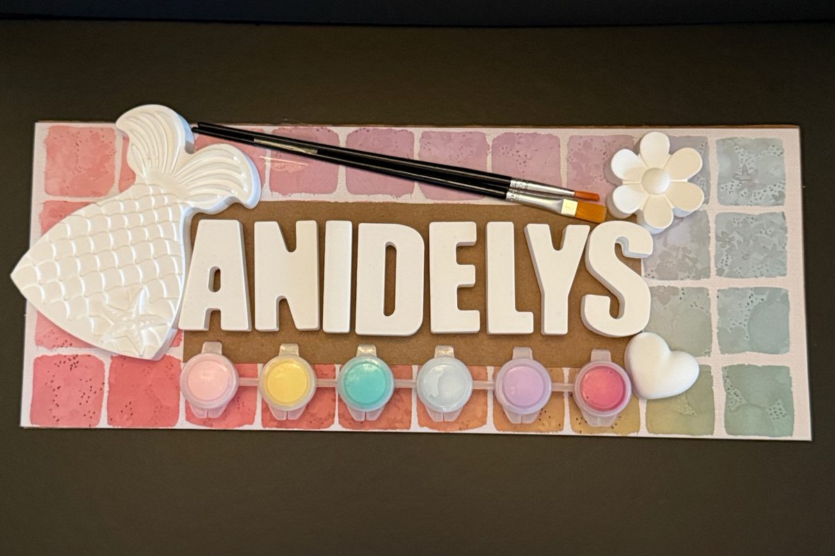 Custom name kit spelling ANIDELYS with a mermaid tail, flower and heart on a pastel tile board, six paints and two brushes.