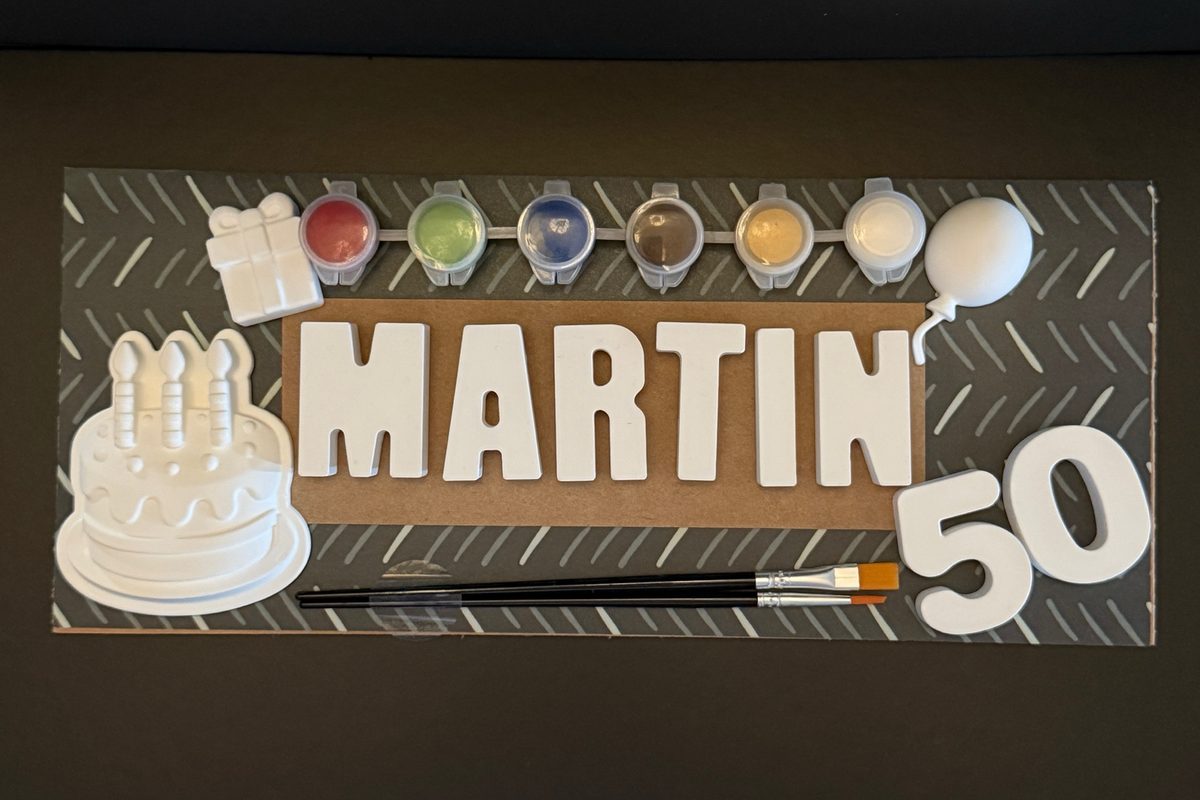 Birthday name kit spelling MARTIN with a birthday cake, present, balloon and the number 50, six paints and two brushes.